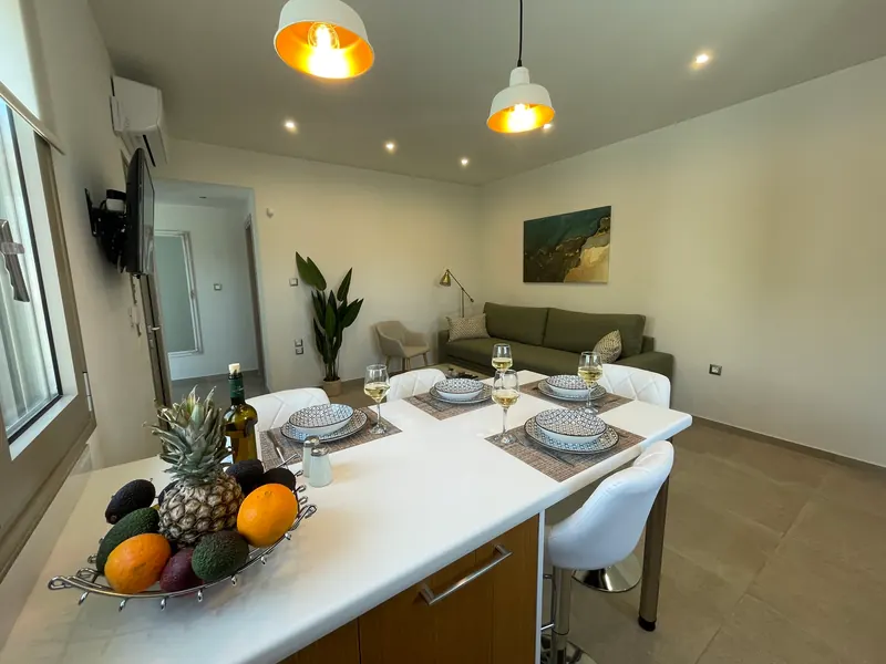 The high table laid for four with patterned bowls, fruit and wine, the living room behind